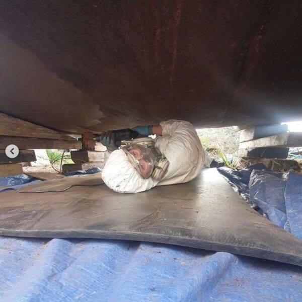 Under the bottom of a springer narrow boat with a rotary blaster tool.